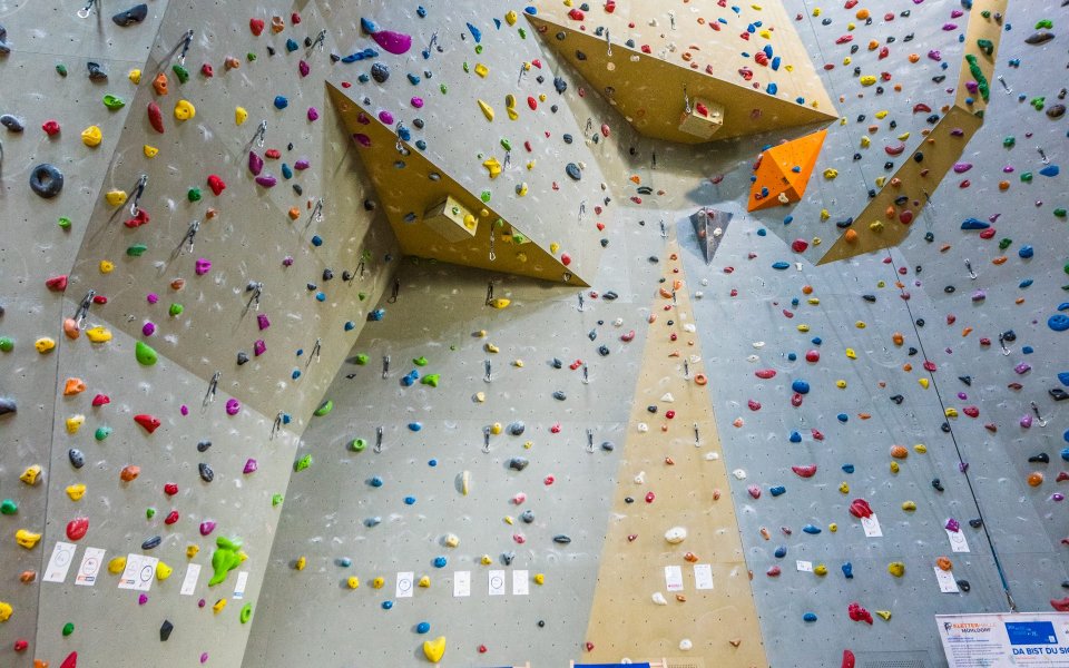 Kletterwand mit zwei blauen Liegestühlen im Vordergrund