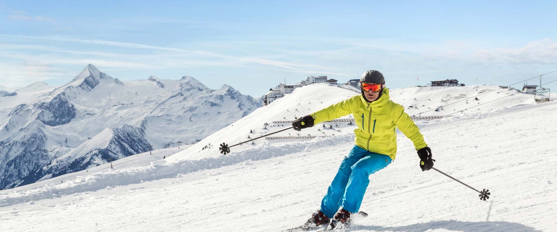 Schifahrer in einem blau grünen Schianzug fährt auf der Piste Schi