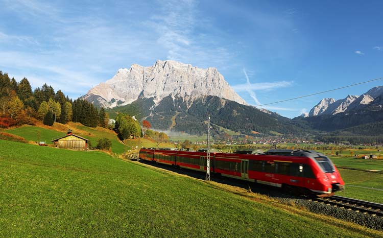 Zug in einer ländlichen Umgebung mit Gebirge im Hintergrund