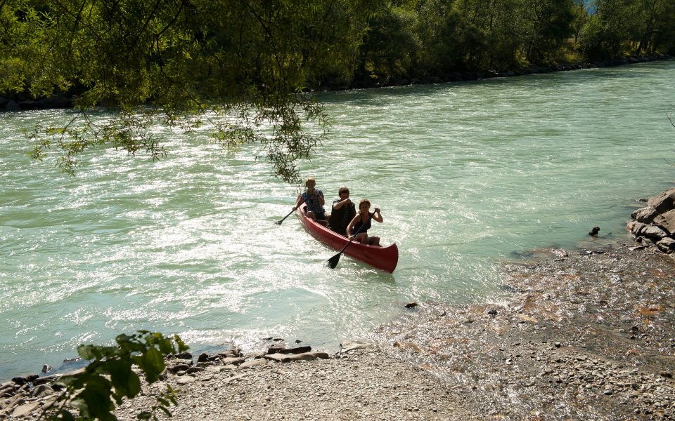 drei Personen sitzen in einem Kanu auf einem Fluss