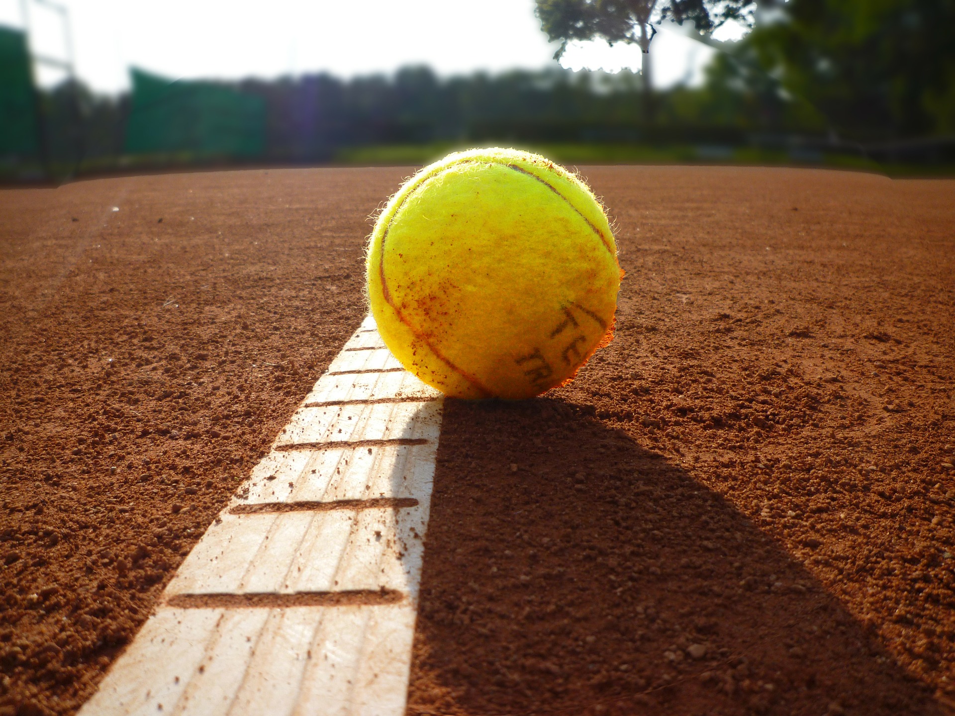 Tennisball auf dem rotem Tennisfeld